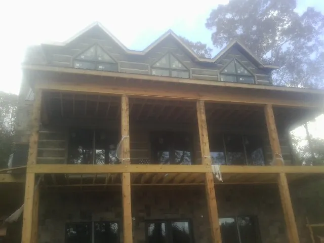 Dormers and porch framing on a large log home under construction — Roof Coating work by our crew in Roslyn